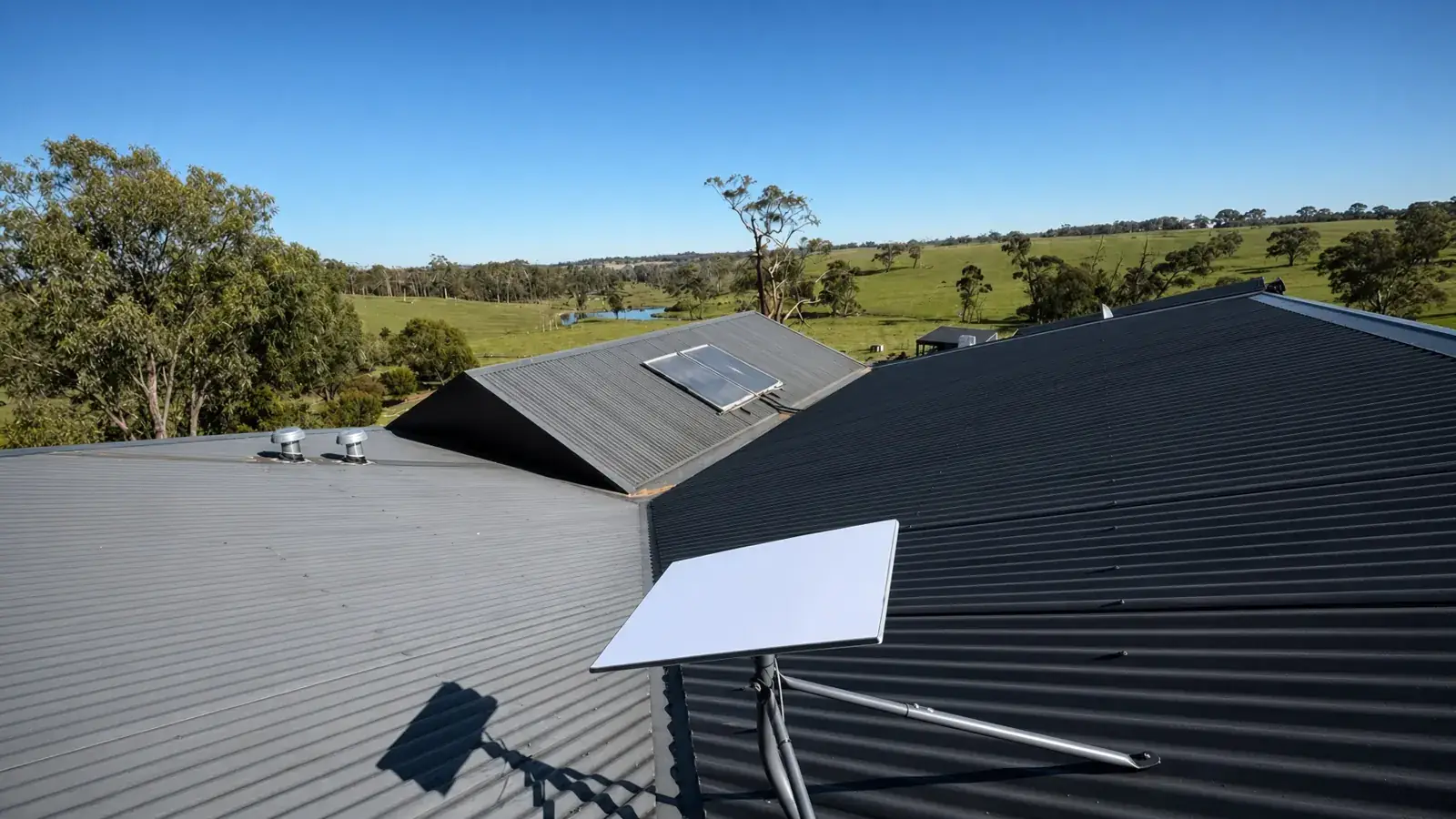 Starlink Standard dish on the Colorbond roof of a rural home in Nyora, looking out over paddocks and a dam. Photo from a VINCONNECT job.
