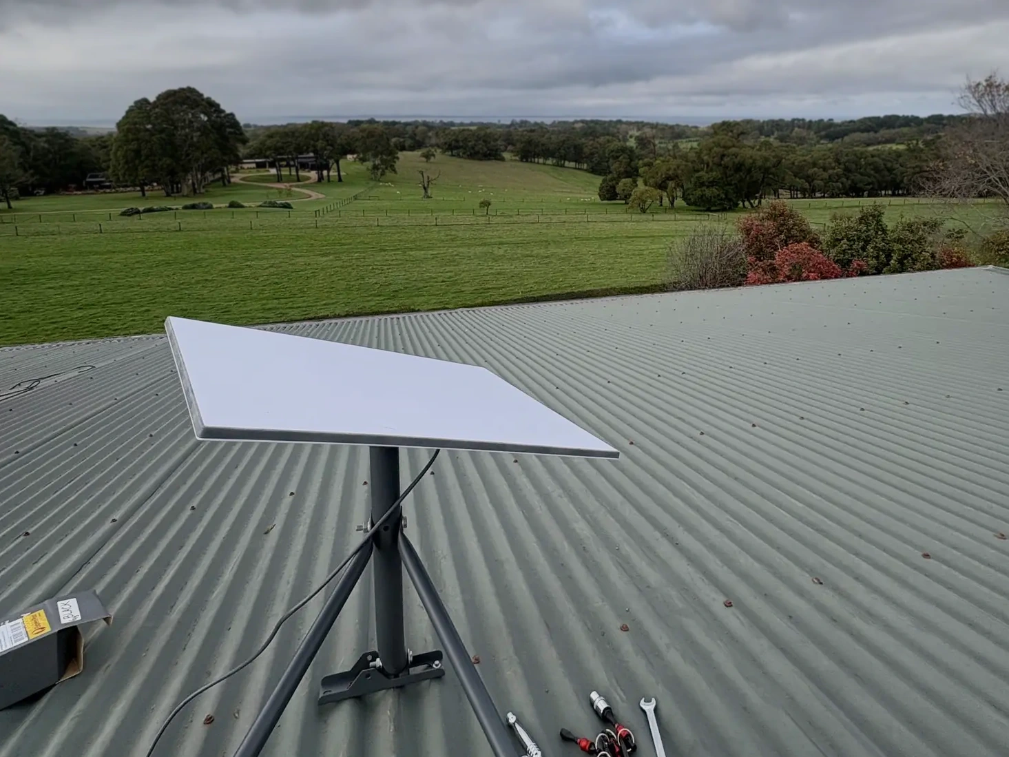 Starlink tripod on the Red Hill metal roof, looking over paddocks and a rural outlook.